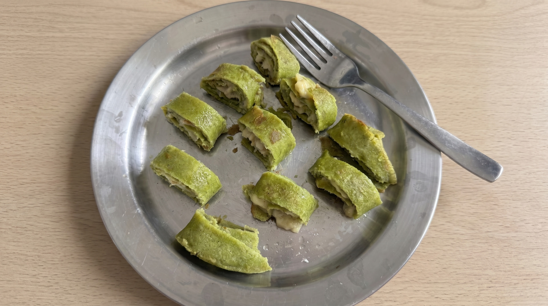 Grøn pandekage rullet med fyld og skåret i skiver på et fad
